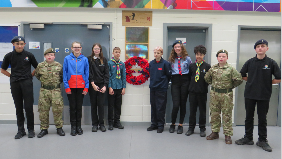 A picture of a group of students wearing their service uniforms  stood around a poppy wreath