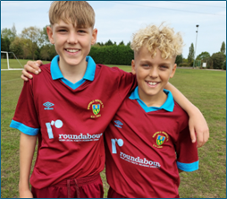 Billy and Zac smiling on a football pitch